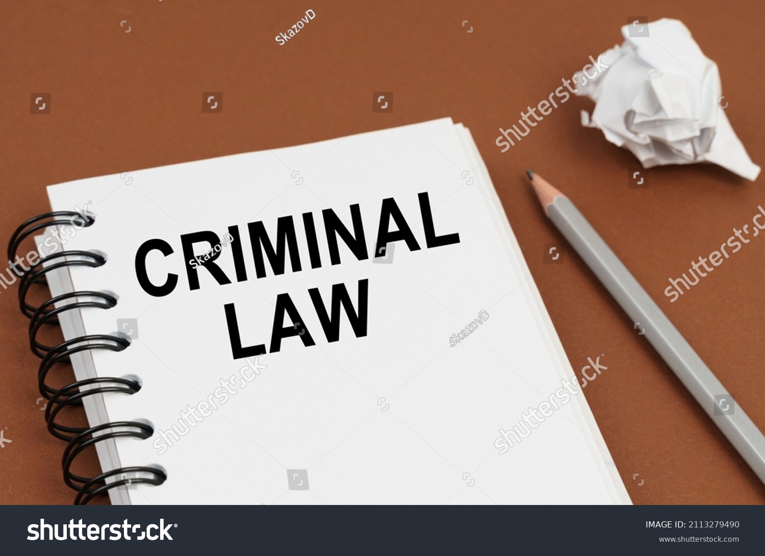 Business and finance concept. On a brown surface lies a pen, crumpled paper and a notepad with the inscription - CRIMINAL LAW #2113279490