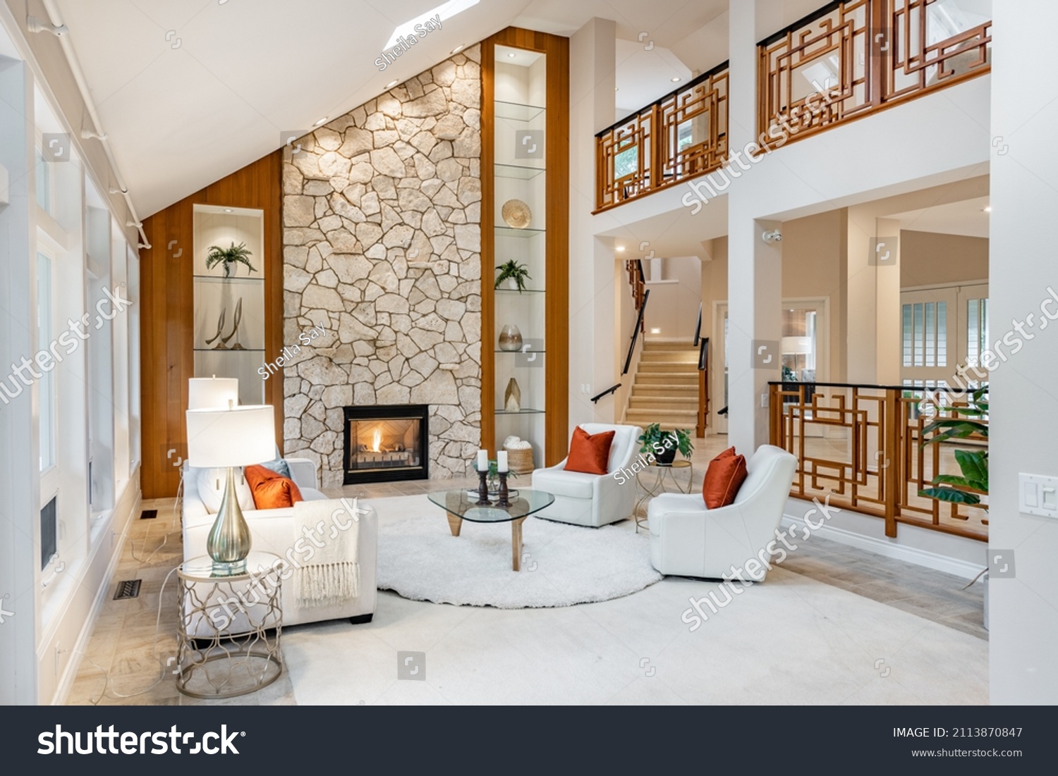 Mid century craftsman house interior living room foyer home office with wood panel walls staircase creative wooden railings stone fireplace in warm white tones and orange accent colors #2113870847