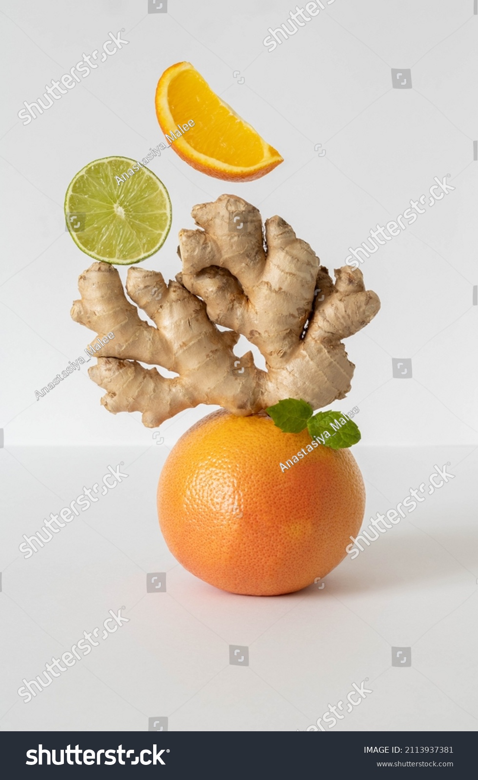 Balancing fruits and vegetables on the table. Equilibrium floating food balance. Fruits levitating on the table: grapefruit, lime, ginger, mint. Pyramid of fruits on a white background. #2113937381