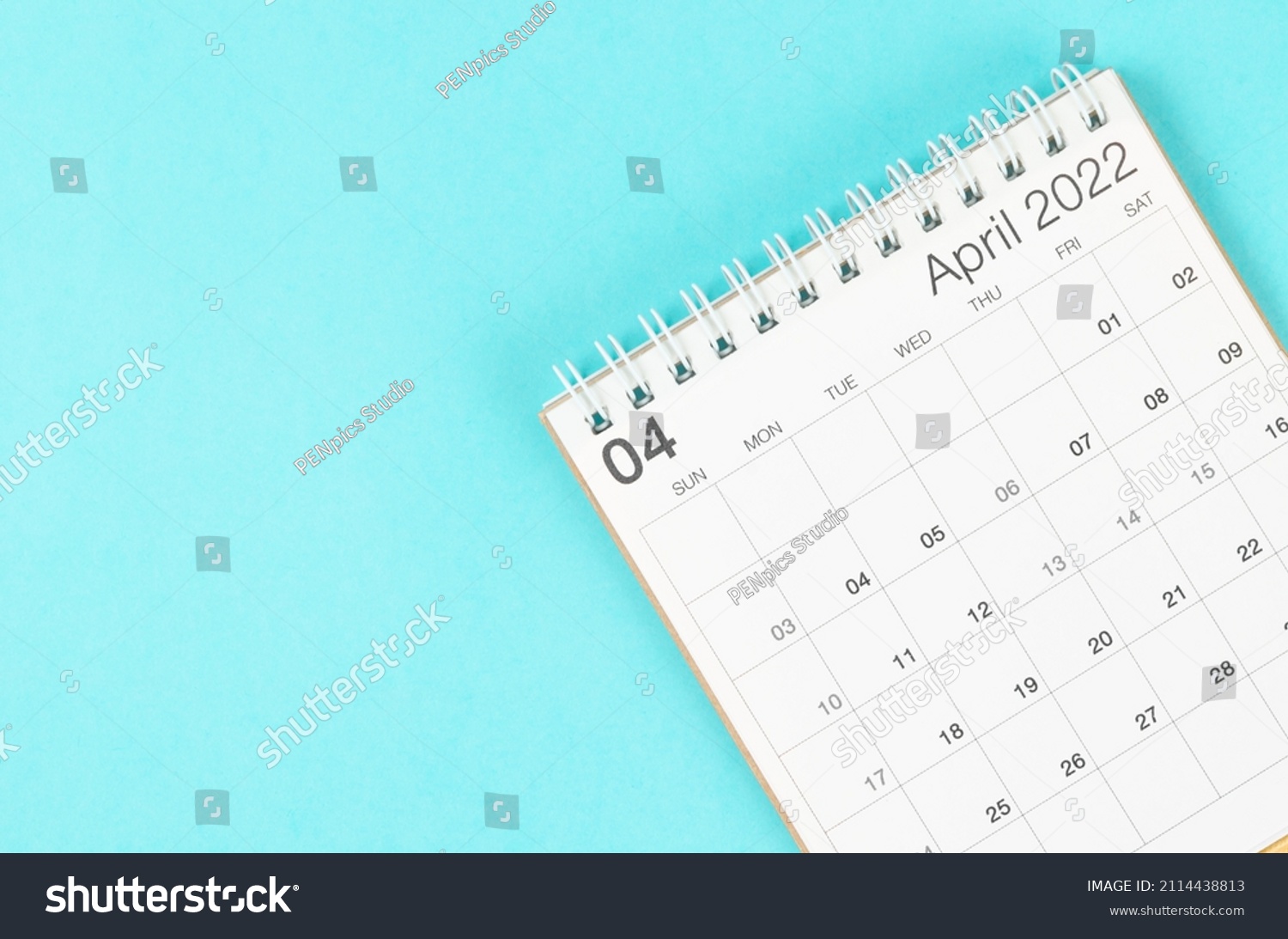 The April 2022 desk calendar on blue background with empty space. #2114438813