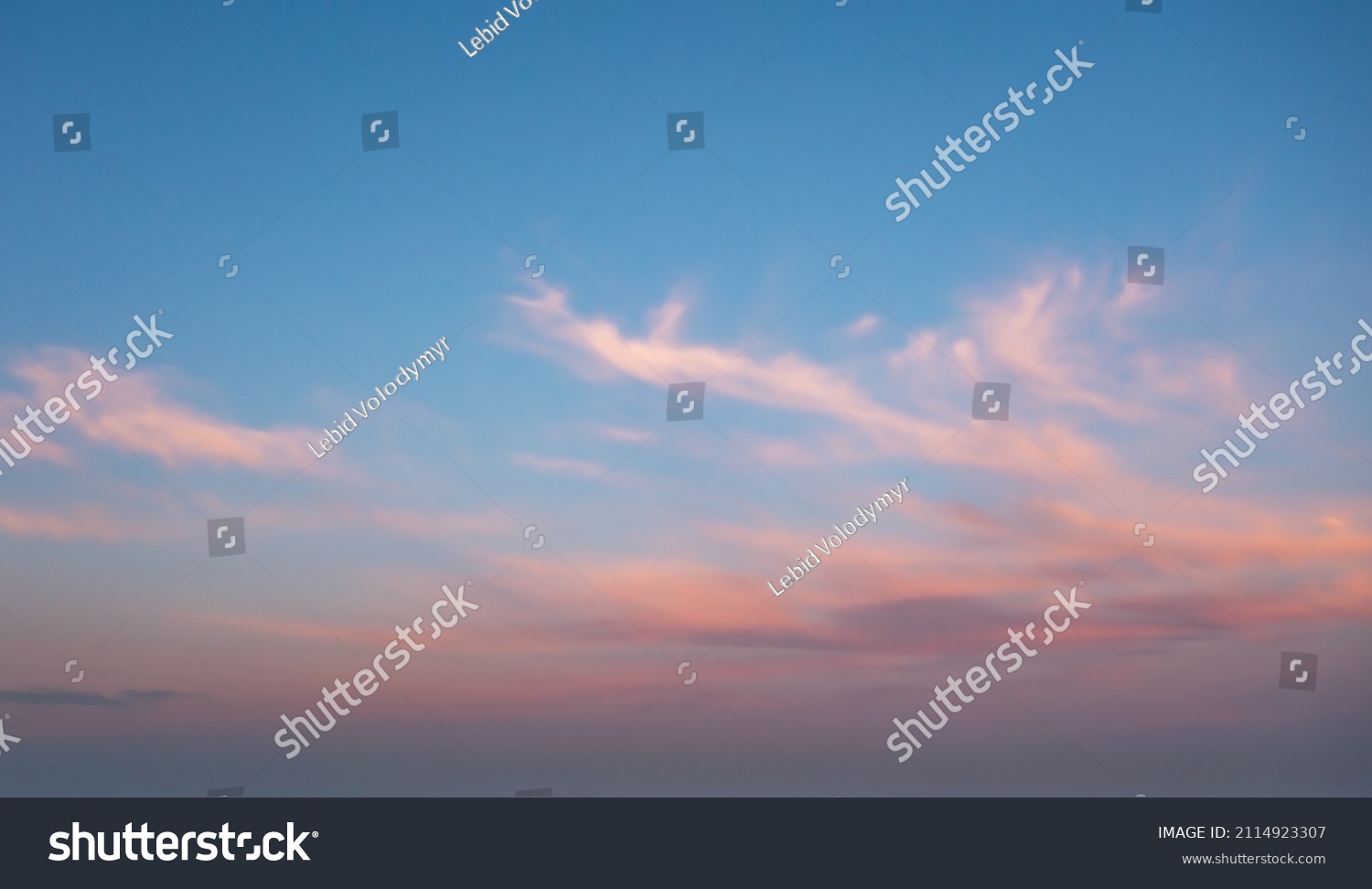 A beautiful sky painted by the sun leaving vibrant gold and pink hues. Clouds in the twilight sky, in the evening. Image of a cloudy sky in the evening. Evening sky scene with golden light  #2114923307
