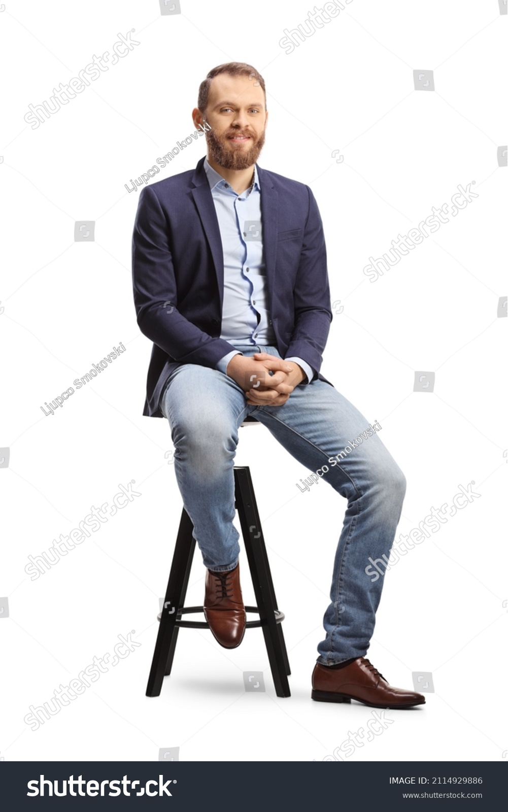 Full length portrait of a man in a suit and jeans sitting on a bar chair isolated on white background #2114929886