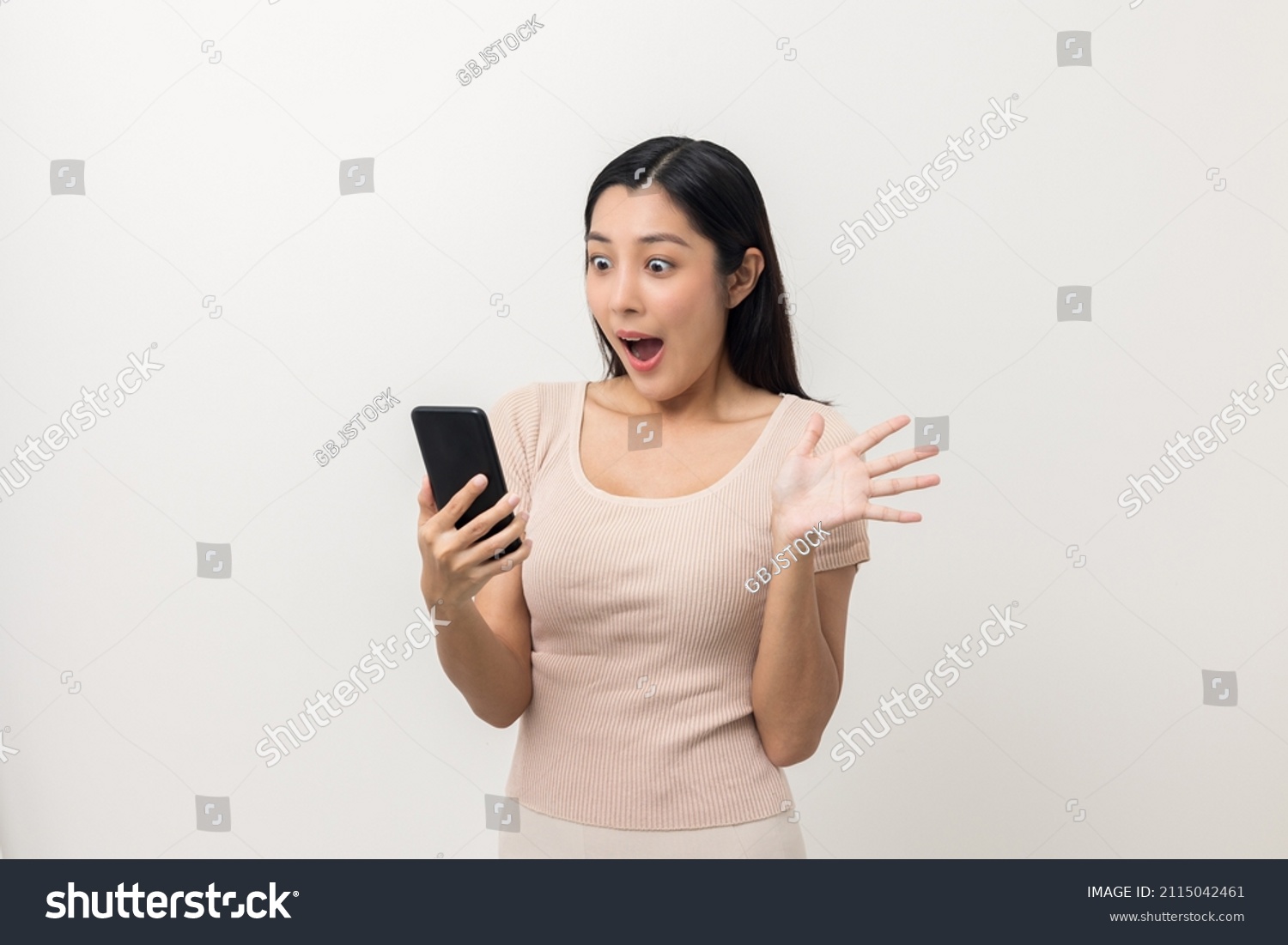 Surprised young Asian lady using mobile phone. Very Shocked face asia woman holding smartphone. Looking at cell phone screen. Victory moment. Very enjoy and fun relax time #2115042461