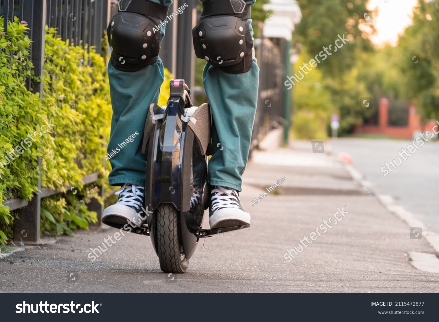 Rider's legs in protective gear on an electric unicycle (EUC). Driving around the city on an electric monowheel. #2115472877
