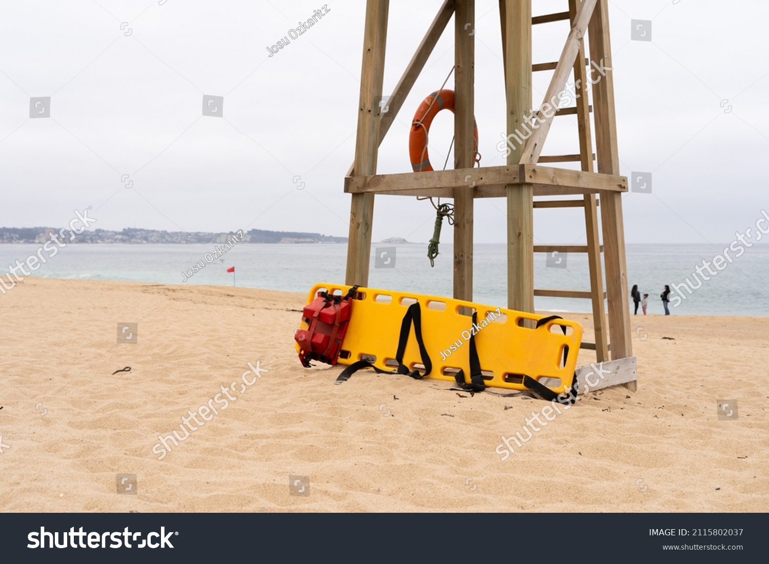 Yellow medical backboard leaning on wooden lifeguard tower on cloudy day in Algarrobo beach, Chile #2115802037