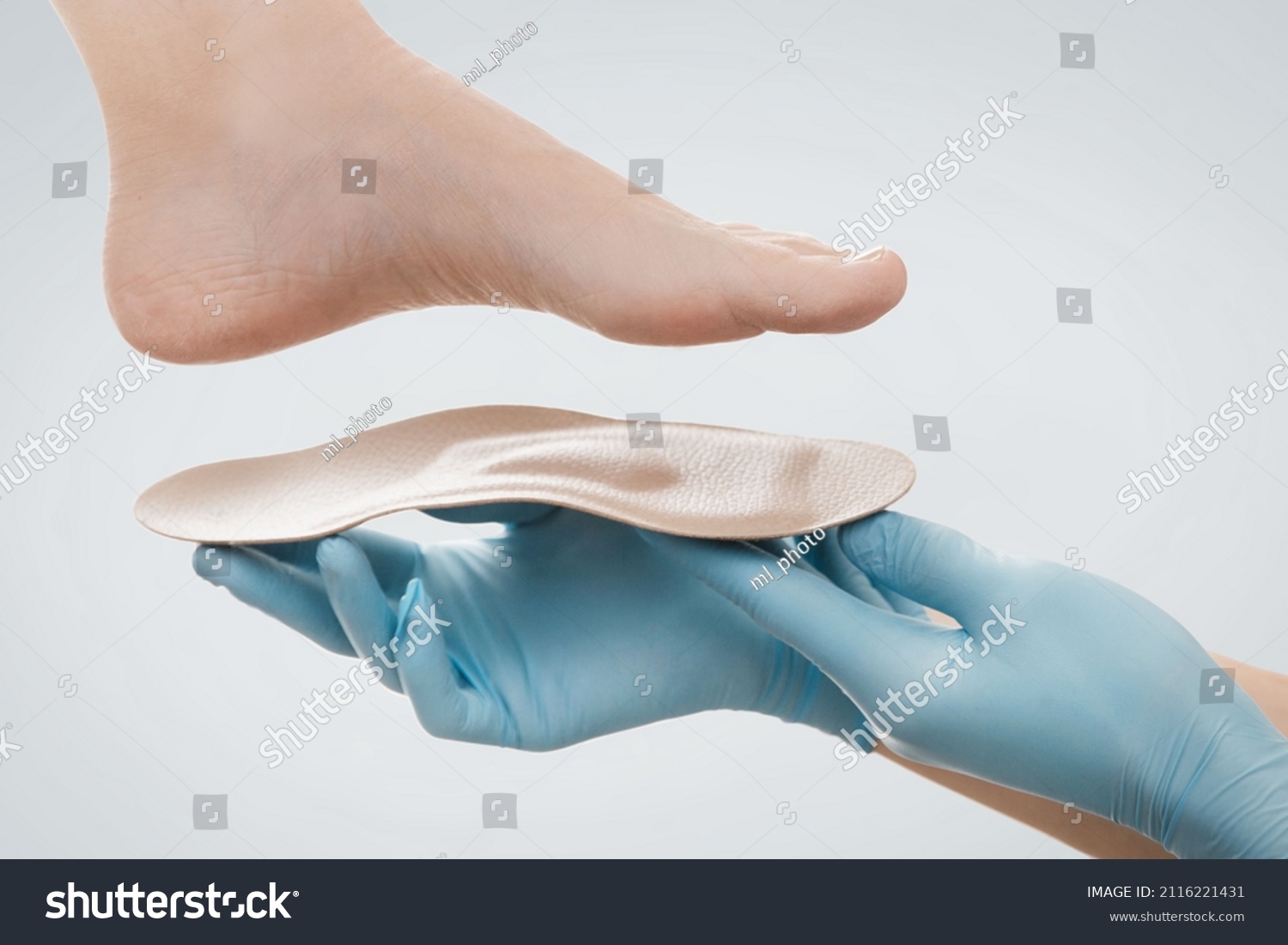 Orthopedic insole isolated on a white background. Hands in rubber gloves hold an orthopedic insole. Foot care, comfort for the feet. Doctor orthopedist tests the medical device. Flat feet correction. #2116221431