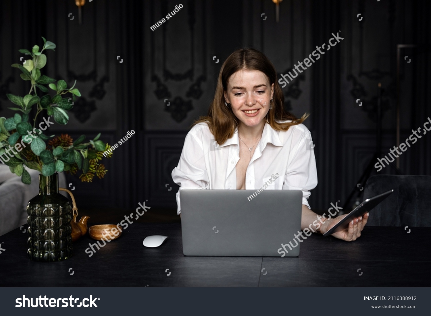 A female receptionist at the hotel works using a laptop, communicating with a client. #2116388912