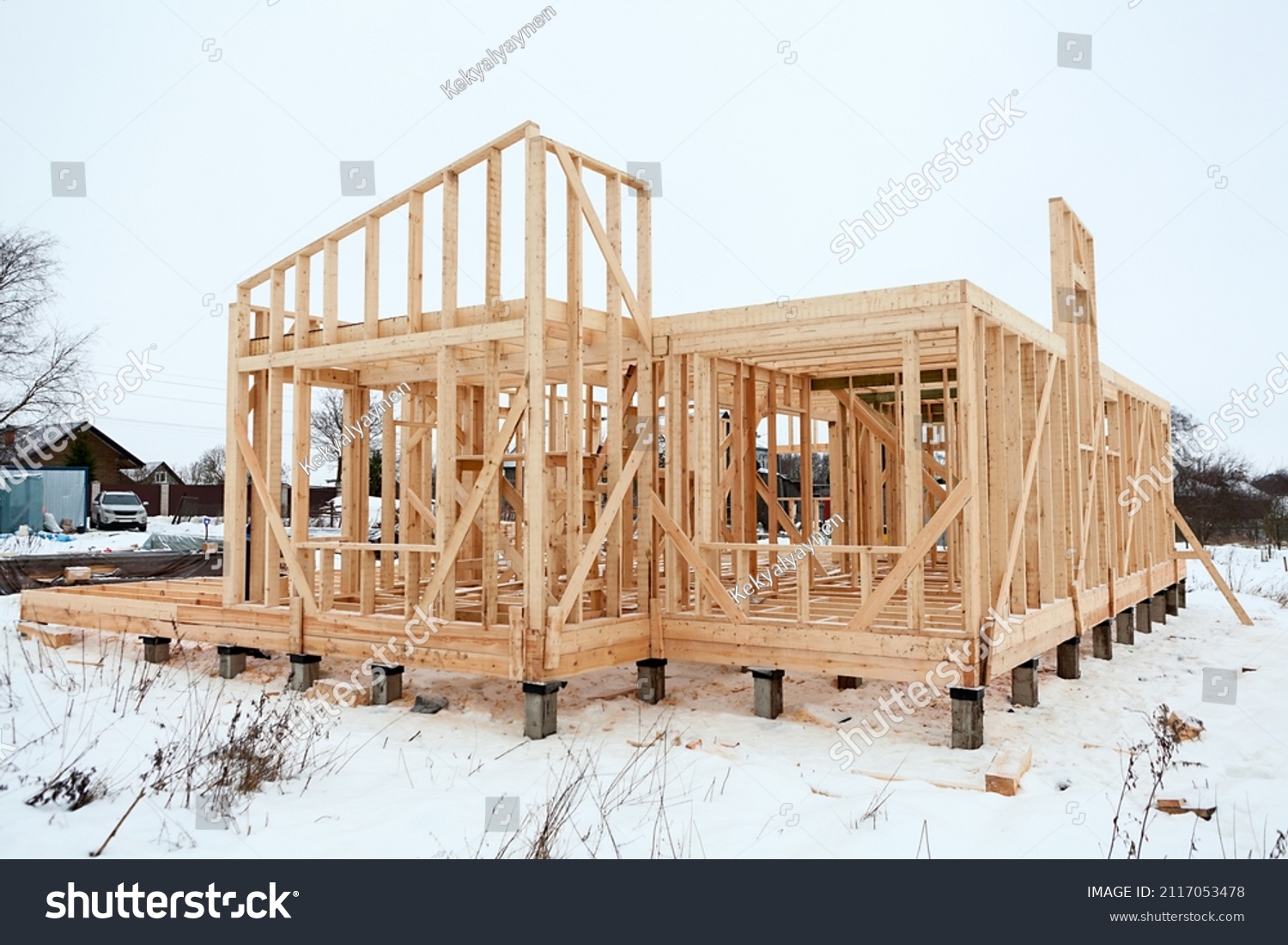 Wood frame house under construction, bare frame and walls with pile foundation, winter season #2117053478