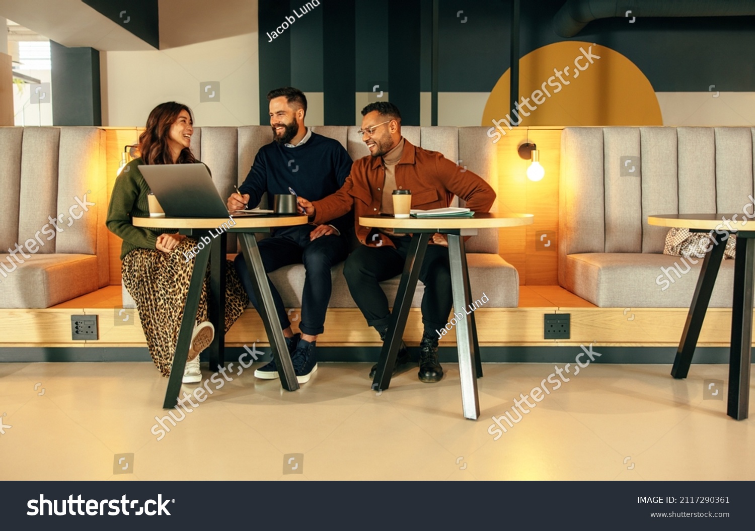 Modern entrepreneurs working together in a lobby. Team of happy businesspeople smiling while having a discussion. Group of entrepreneurs collaborating on a new project in a co-working space. #2117290361
