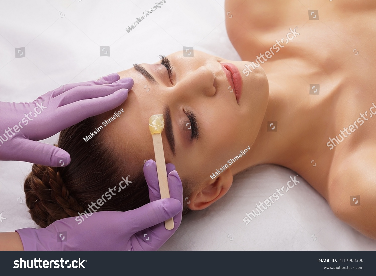 Beautician is removing hair from beautiful female face with hot wax. Woman has a beauty treament procedure. Depilation, epilation, skin and health care concepts. #2117963306
