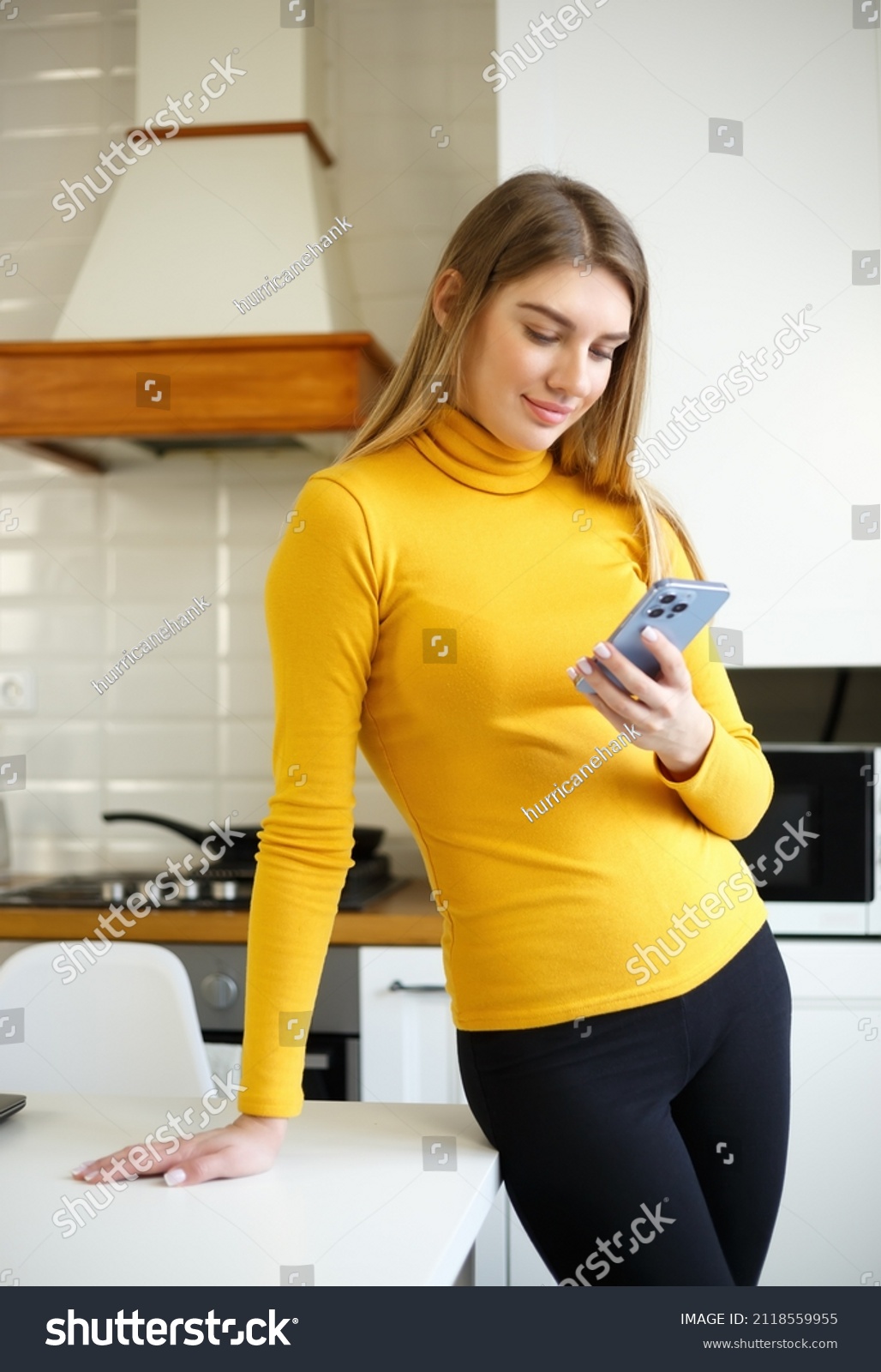 Happy blonde girl browsing a mobile app on a smartphone at home  #2118559955