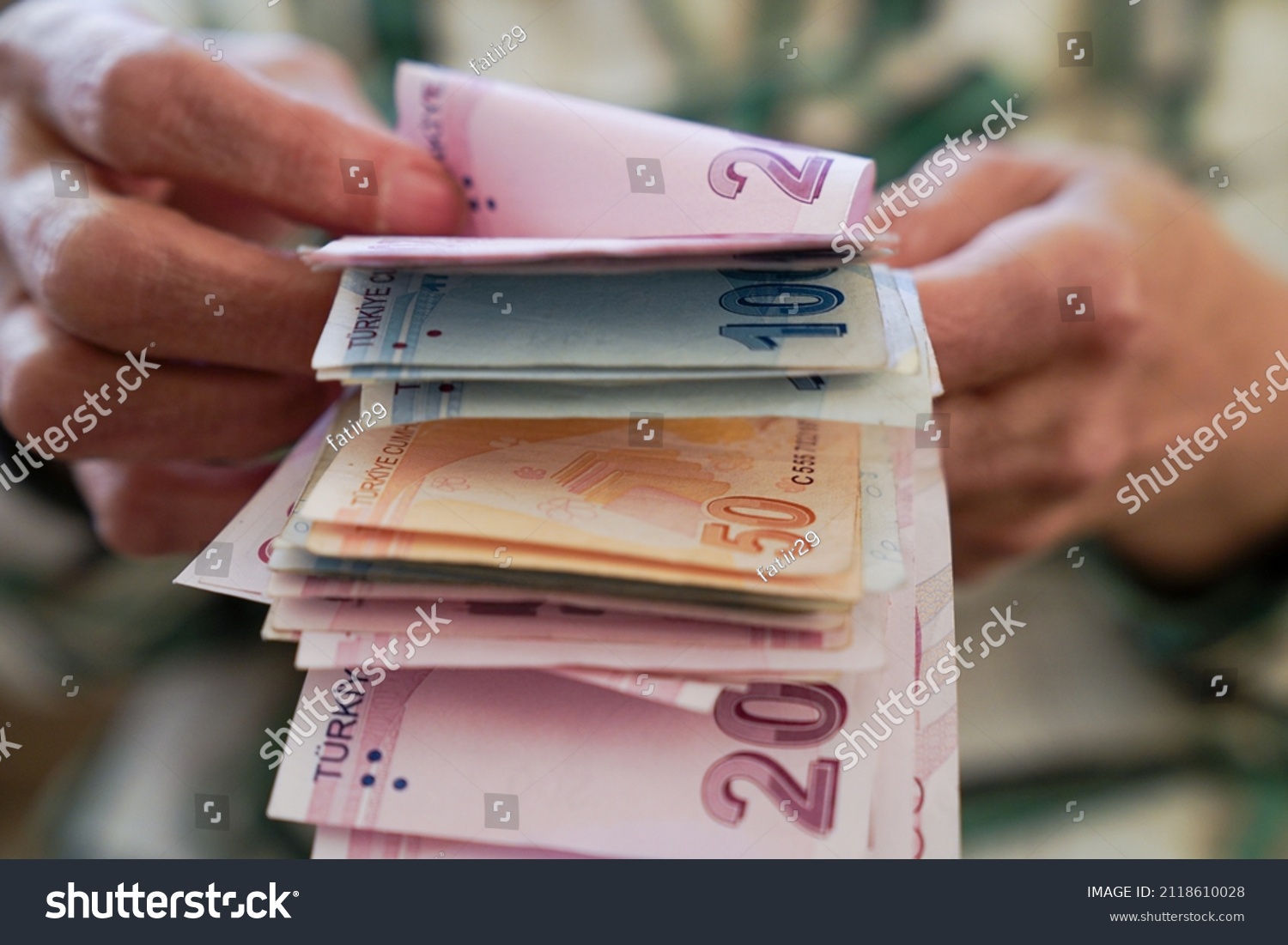 Closeup of wrinkled hands holding turkish lira banknotes              #2118610028