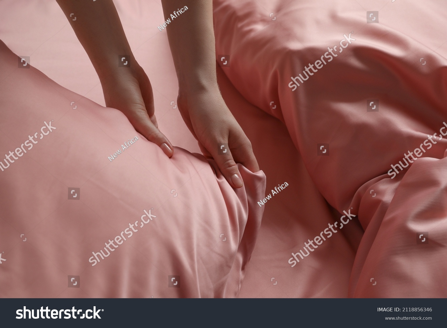 Woman making bed with beautiful pink silk linens, closeup view #2118856346