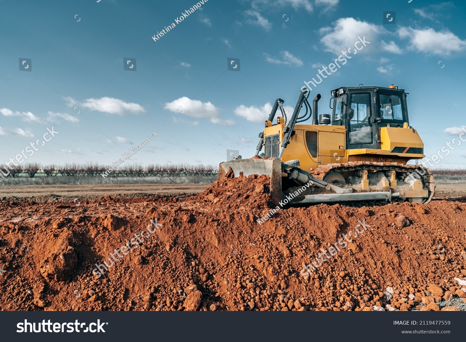 Crawler bulldozer working on construction site or quarry. Mining machinery moving clay, smoothing gravel surface for new road. Earthmoving, excavations, digging on soils. #2119477559