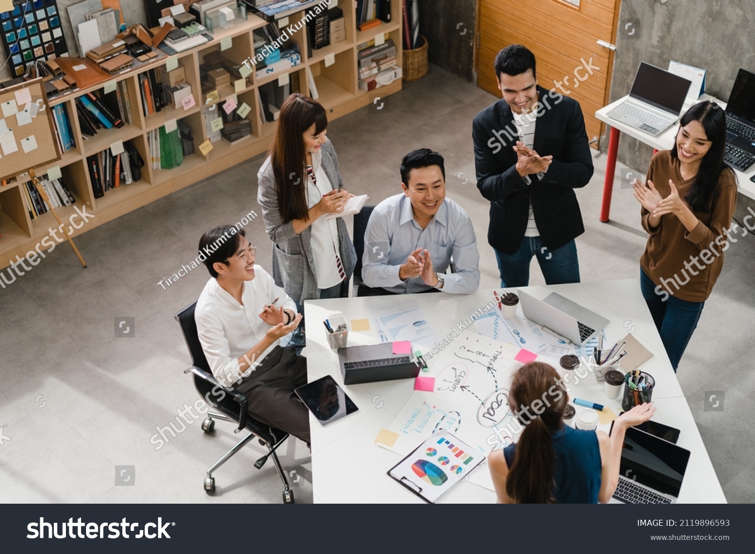 Multiracial group of Asia young creative people in smart casual wear discussing business clapping, laughing and smiling together in brainstorm meeting at office. Coworker teamwork successful concept. #2119896593