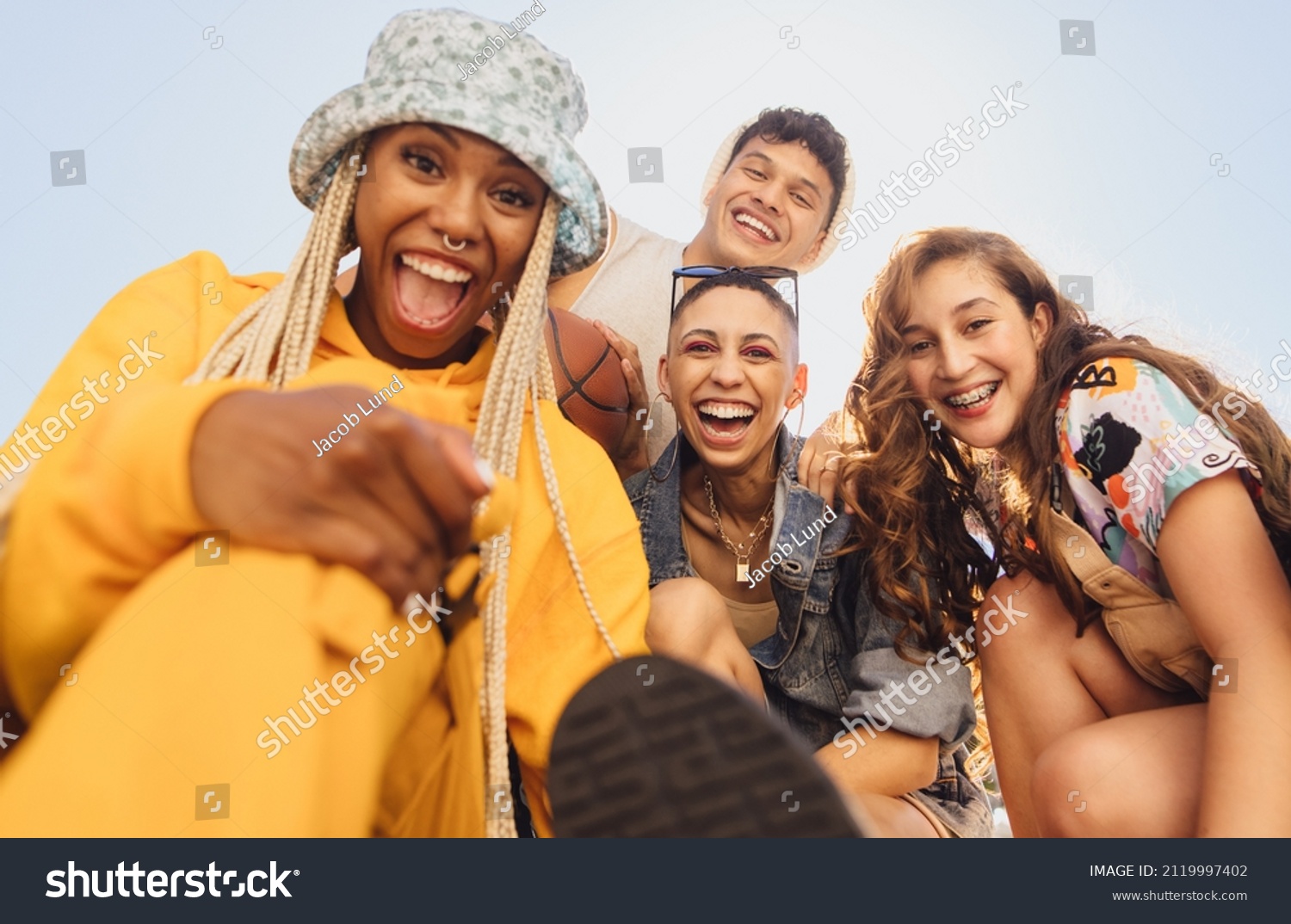 Cheerful generation z friends having fun together outdoors. Group of multiethnic friends smiling at the camera cheerfully. Vibrant young people making happy memories together. #2119997402