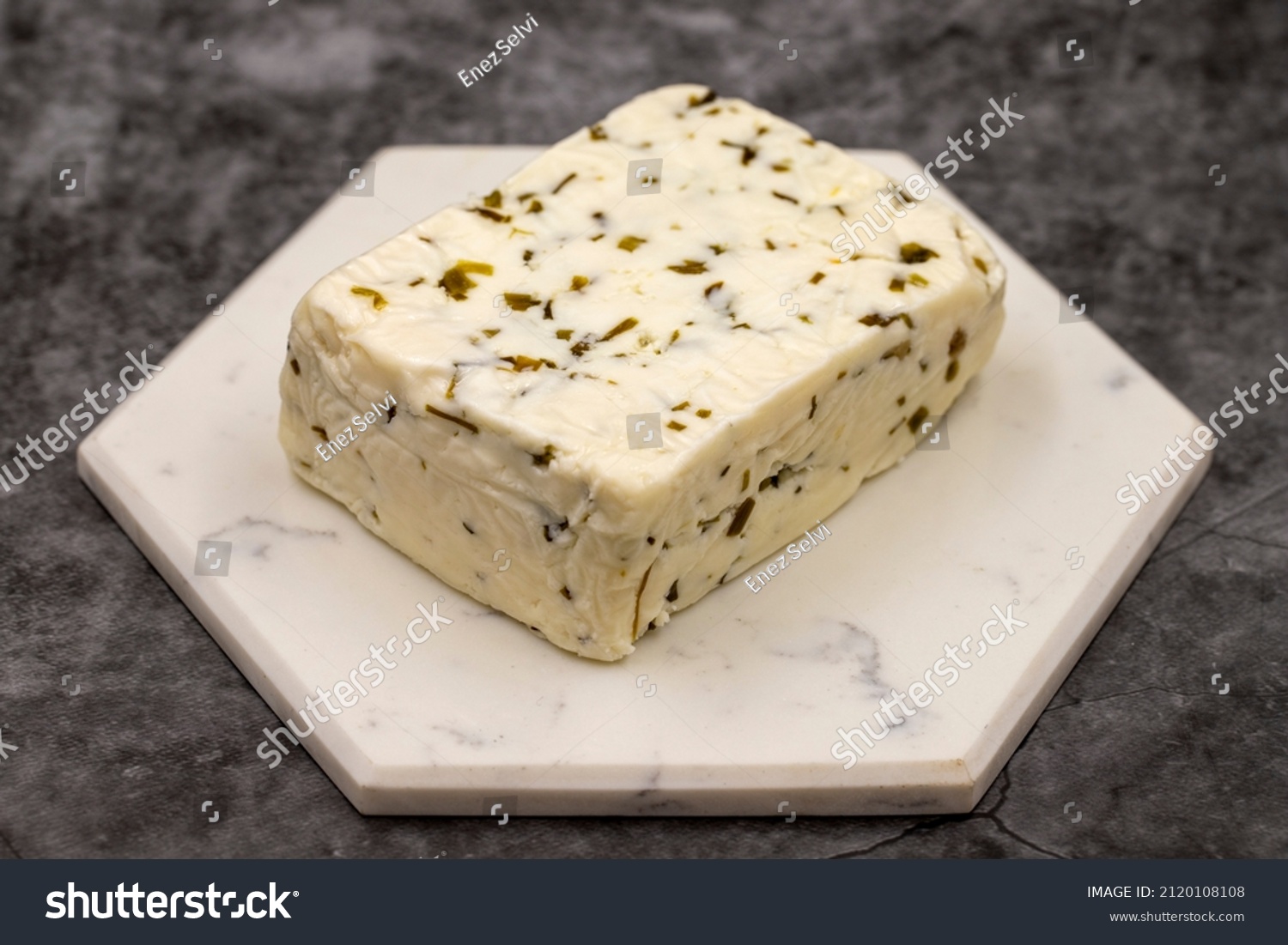 Cheese with herbs on a dark background. Minced goat feta cheese with herbs. Traditional Mediterranean cheese. Local name otlu peynir #2120108108