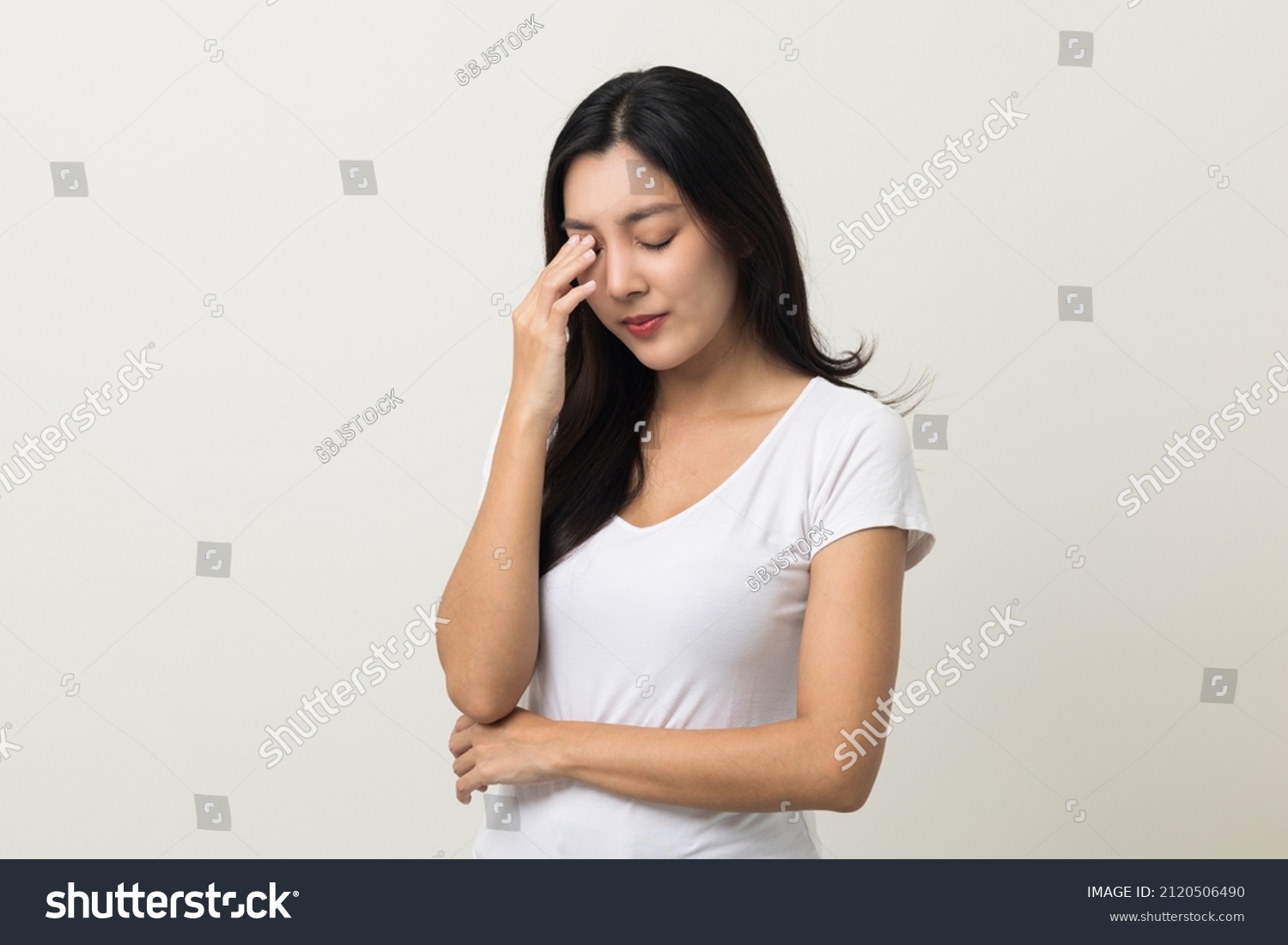 Young asian beautiful woman hand rubbing eyes she's feeling depressed stress headache be tired from working standing on isolated white background she has health problems. #2120506490