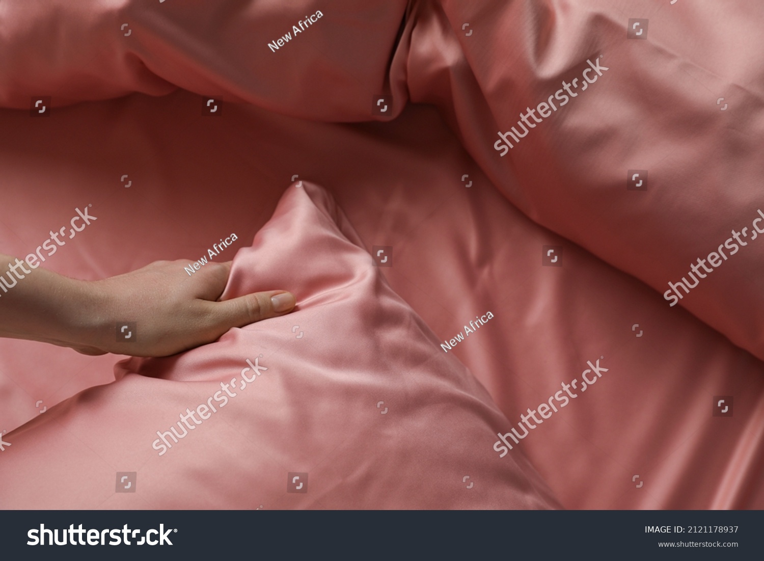Woman making bed with beautiful pink silk linens, closeup view #2121178937