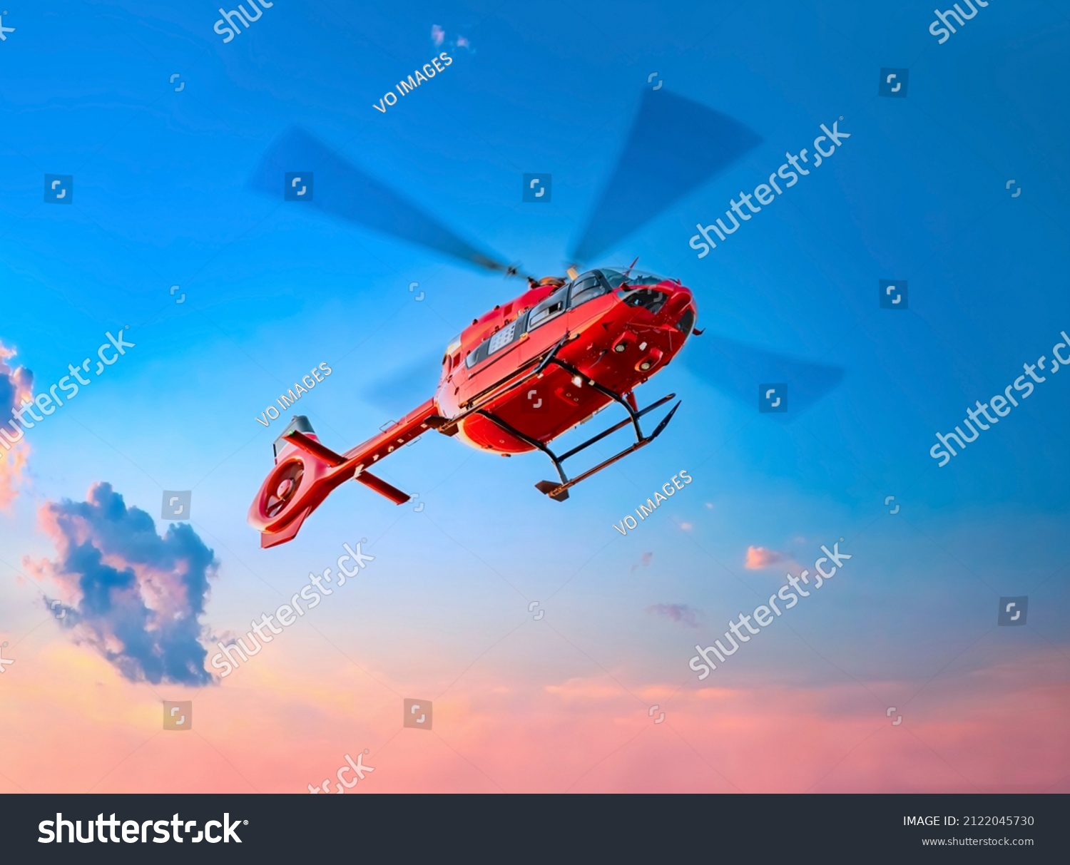 Red color helicopter in the air. Great photo on the theme of air medical service, air transportation,  air ambulance,  fast city transportation or helicopter tours.  #2122045730