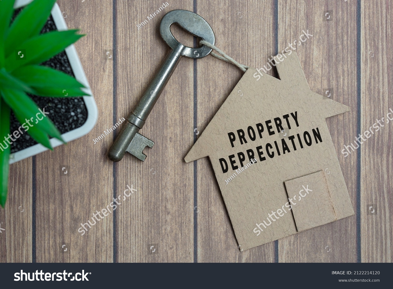 Property depreciation text on house model and key on wooden desk #2122214120