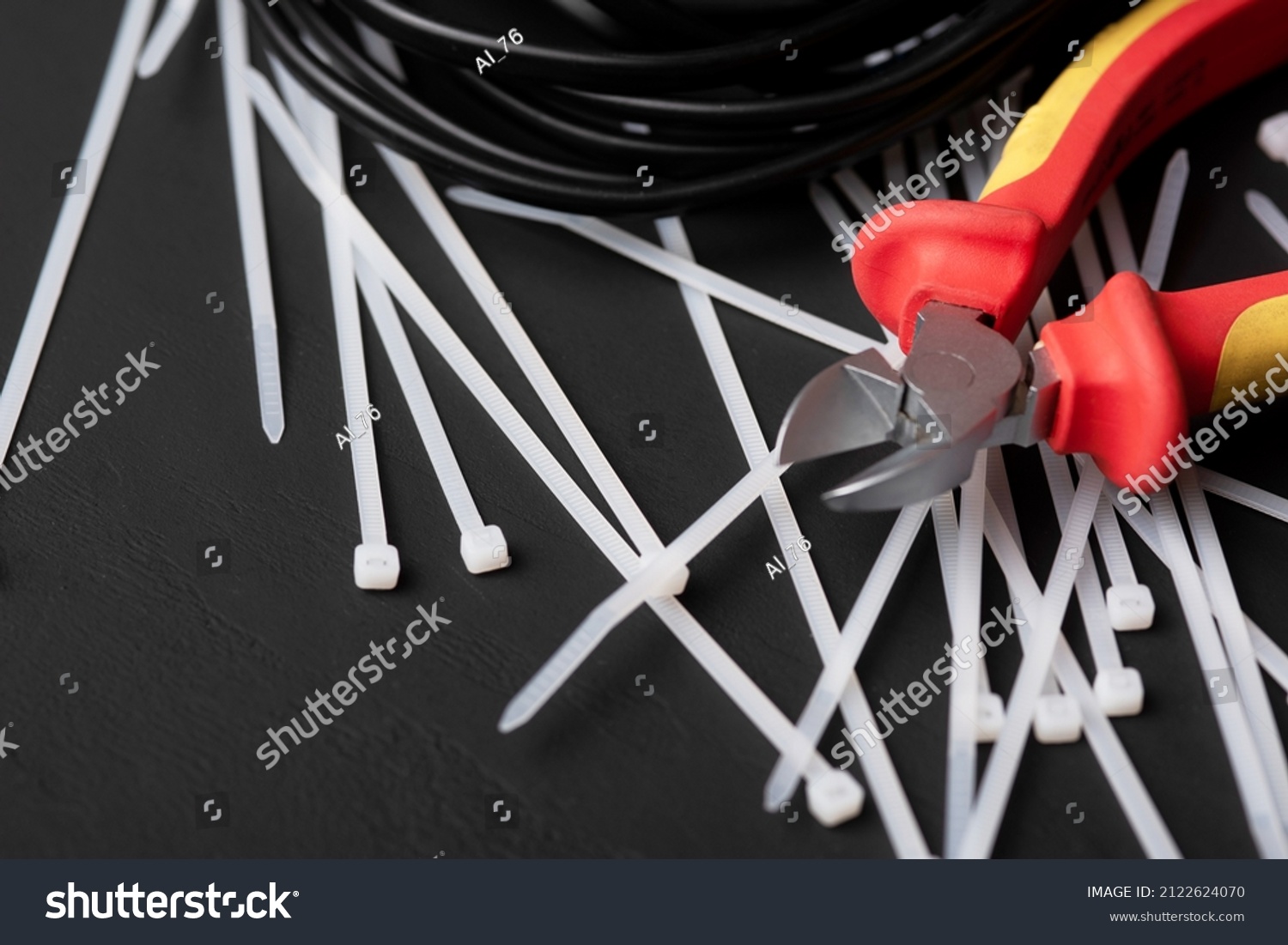 wire cutters with electric cables and cable ties on a black background with a place for the inscription #2122624070