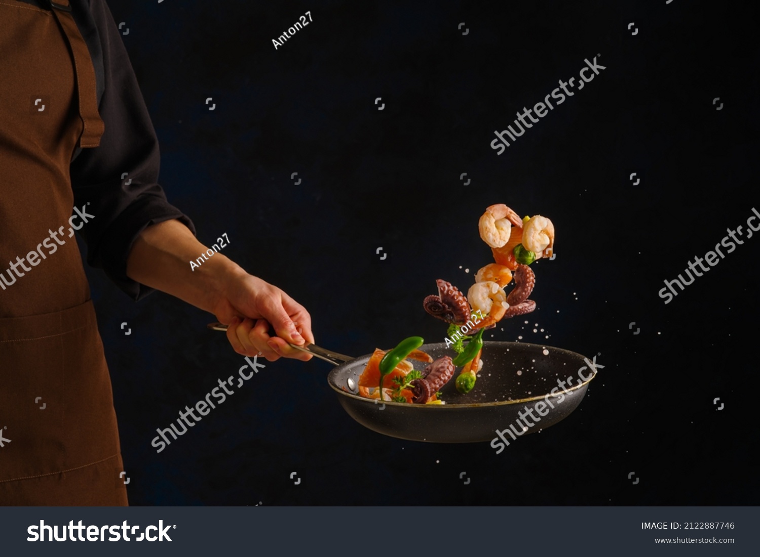Cooking seafood - shrimp, octopus with vegetables in a frying pan on a black background by a professional chef. Frozen in-flight food. Sea food. Vegetarian, diet food. Banner. #2122887746