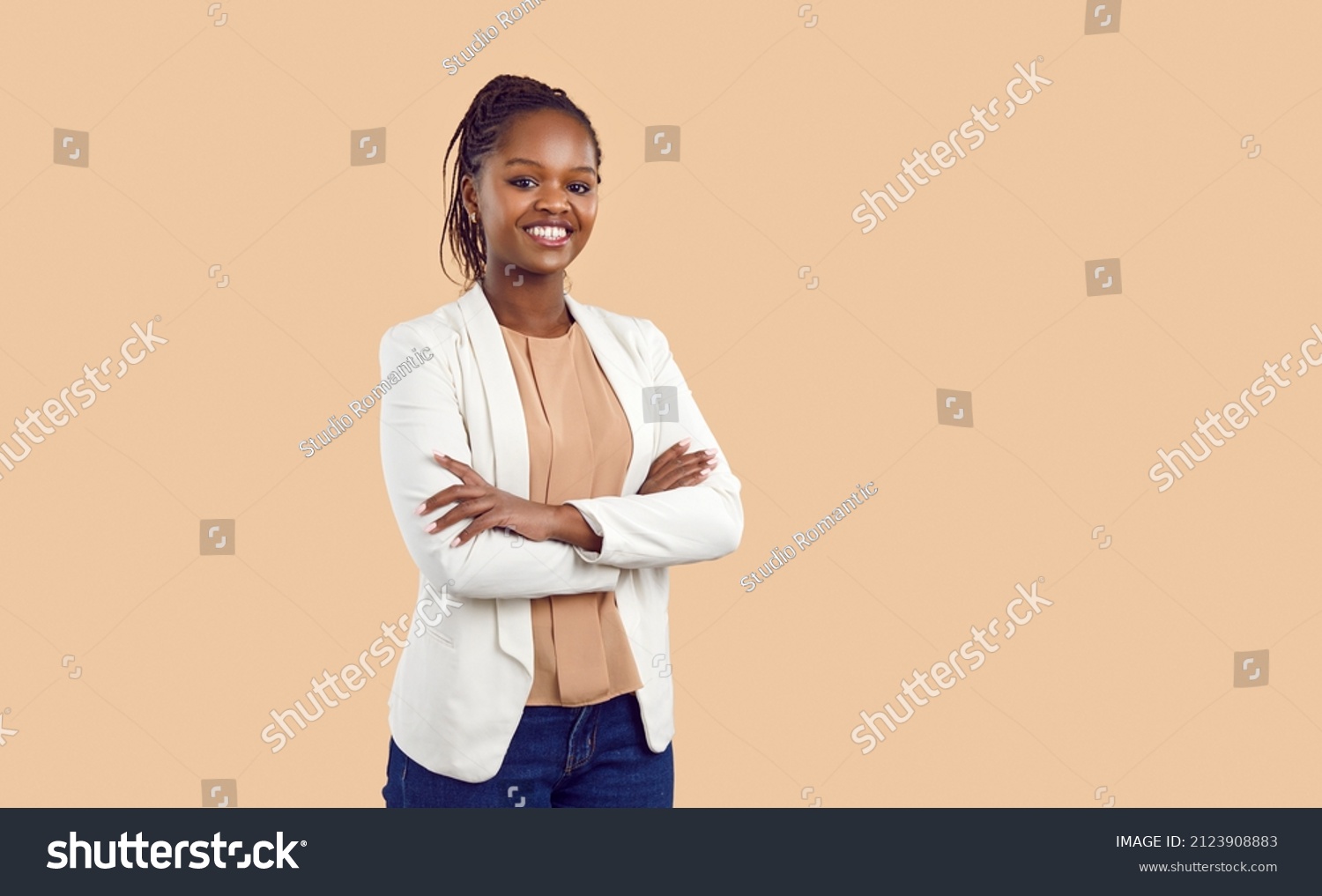 Studio portrait of happy successful confident black business woman. Beautiful young lady in white jacket smiling at camera standing isolated on blank solid beige colour copyspace background #2123908883