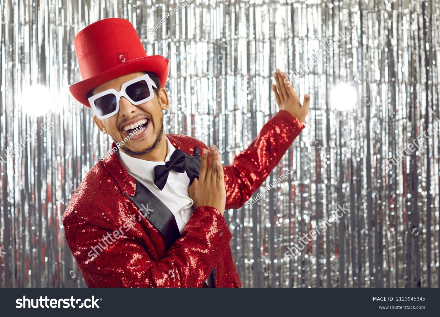 Happy young black man in red disco jacket dance on glitter background. Smiling African American entertainer or showman have fun on party or celebration in nightclub. Entertainment concept. #2123945345