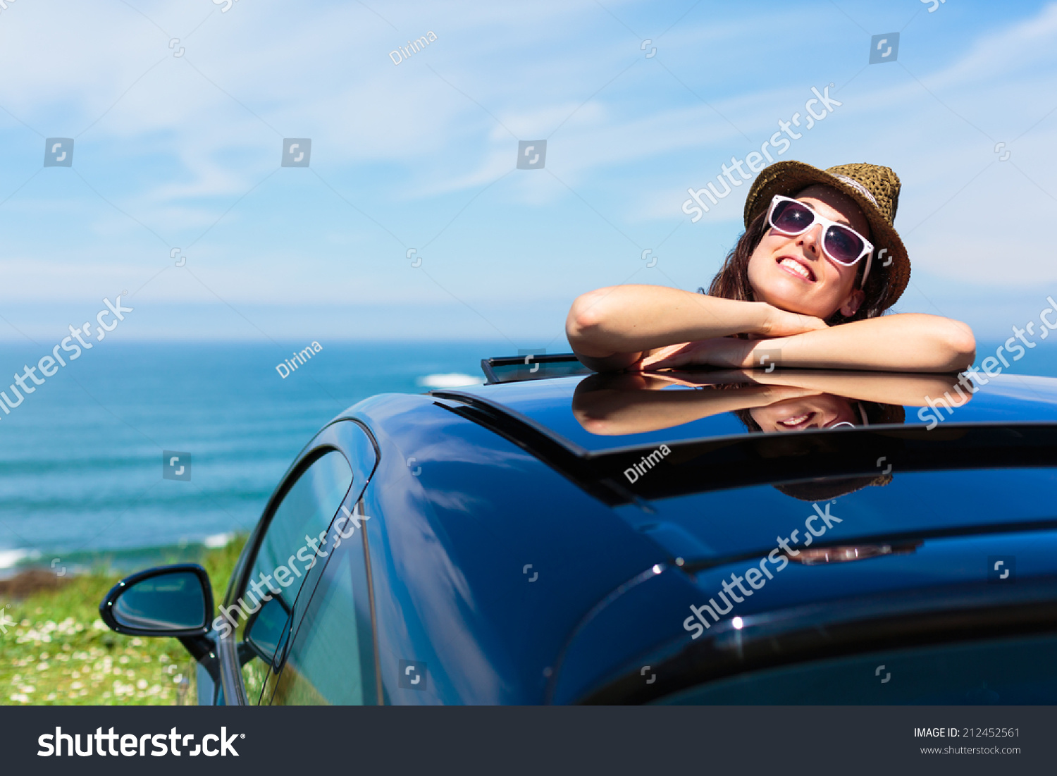 Relaxed day dreaming woman on summer travel vacation leaning out car sunroof towards the sea. #212452561