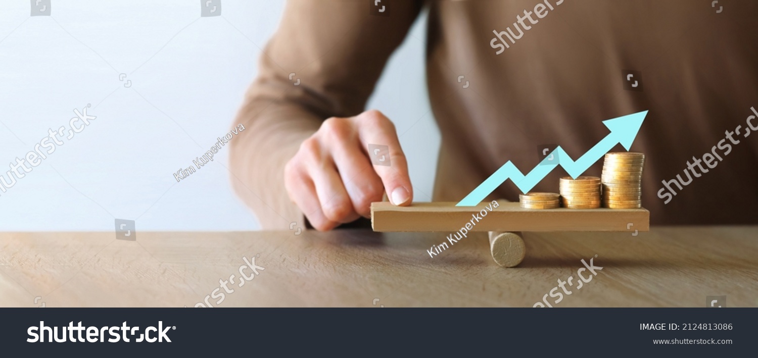 Money leverage and inflation balance. Businesswoman Balancing Stacked Coins With Finger On Wooden Seesaw. Financial concept #2124813086