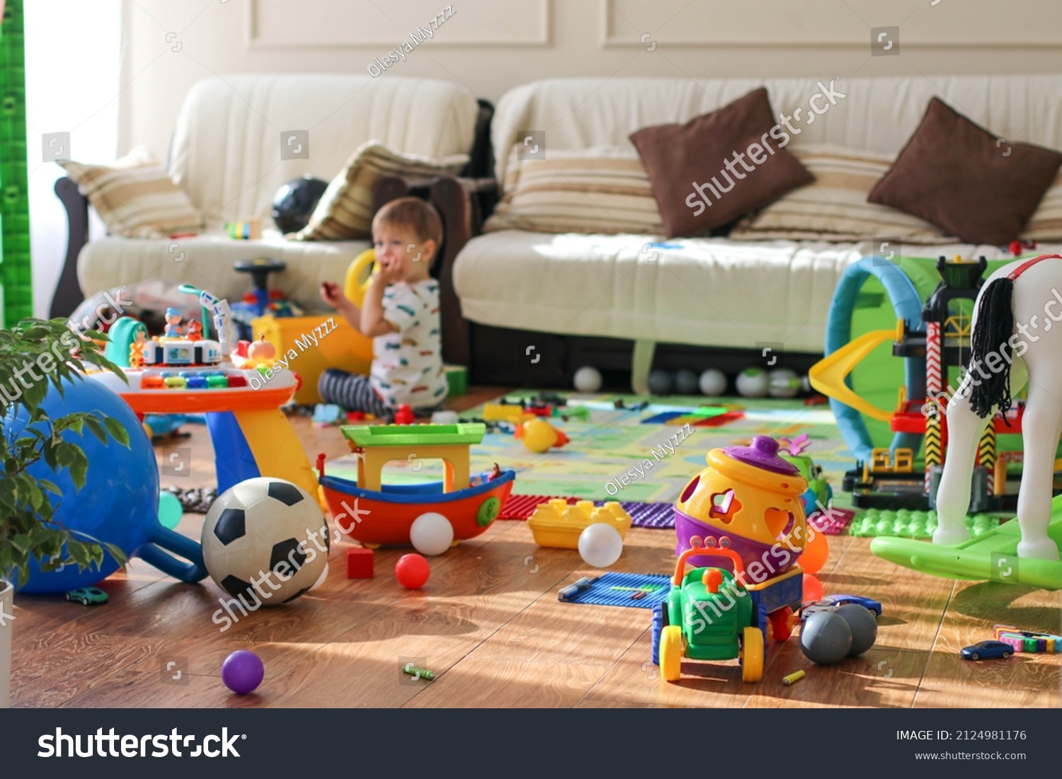 Adorable toddlers playing among the many toys at home. A mess in the children's room, a lot of toys in the children's room. Dirty house. Children's room #2124981176