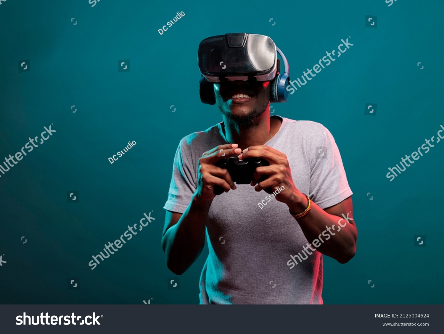 African american guy playing video game with controller and vr headset, enjoying online play with futuristic 3d simulation in studio. Gamer with virtual reality glasses holding joystick. #2125004624