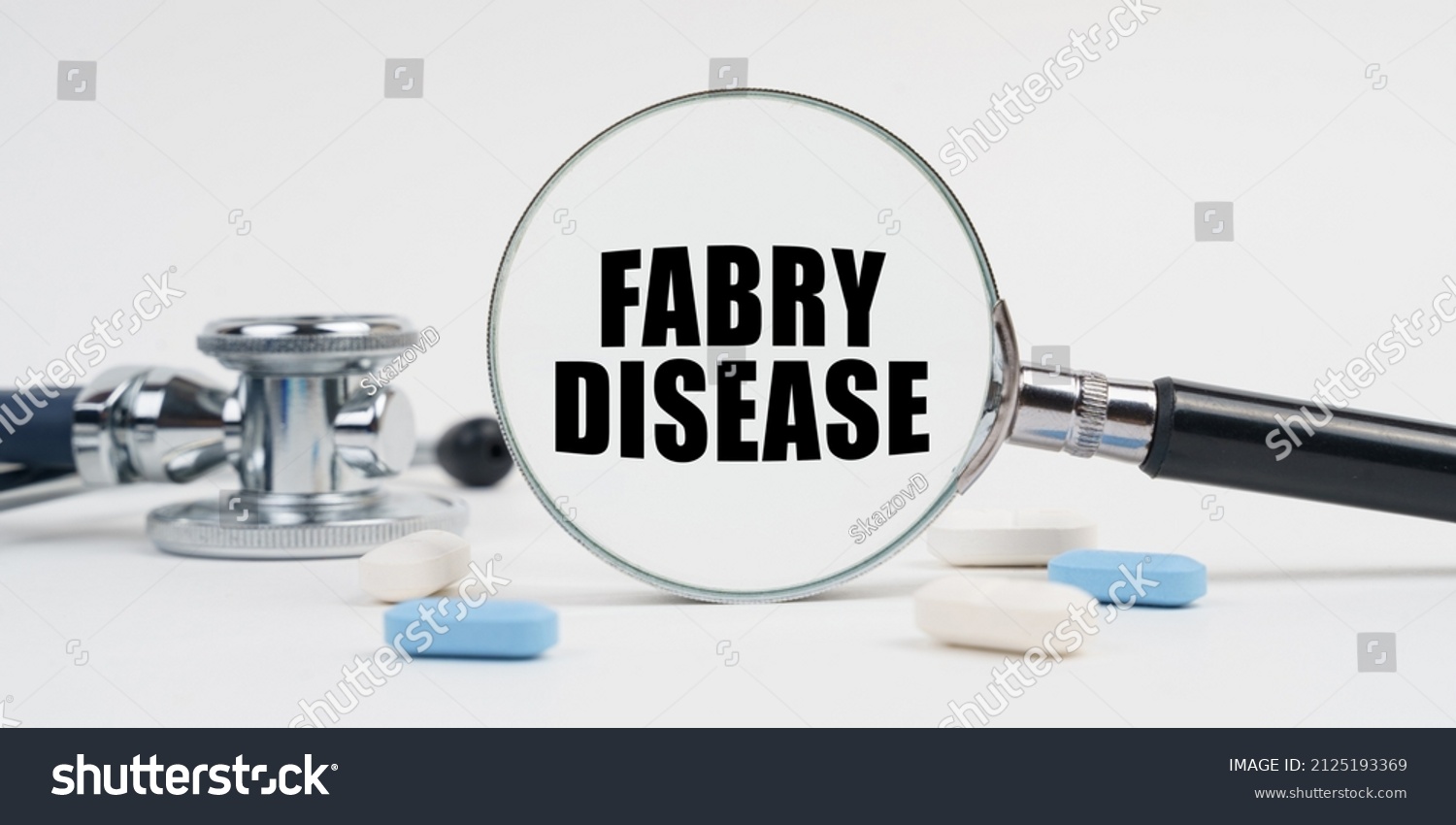 Medicine and health concept. On a white surface lie pills, a stethoscope and a magnifying glass with the inscription - FABRY DISEASE #2125193369