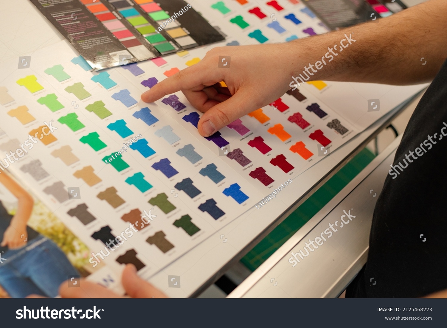 Cropped man hand choosing samples catalog multicolor advertising T-shirts palette film membrane. Textile production #2125468223