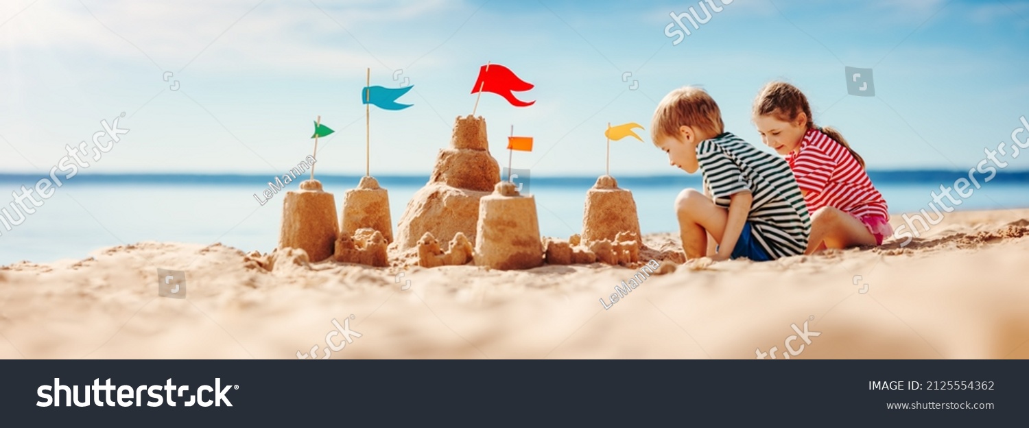 Boy and girl playing on the beach on summer holidays. Children building a sandcastle at the sea. #2125554362
