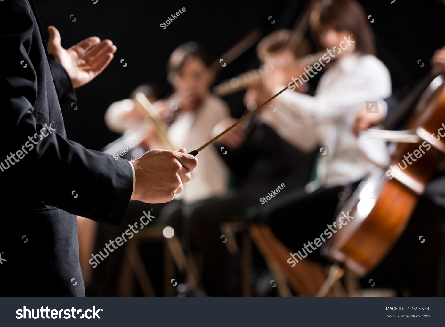 Conductor directing symphony orchestra with performers on background, hands close-up. #212595574