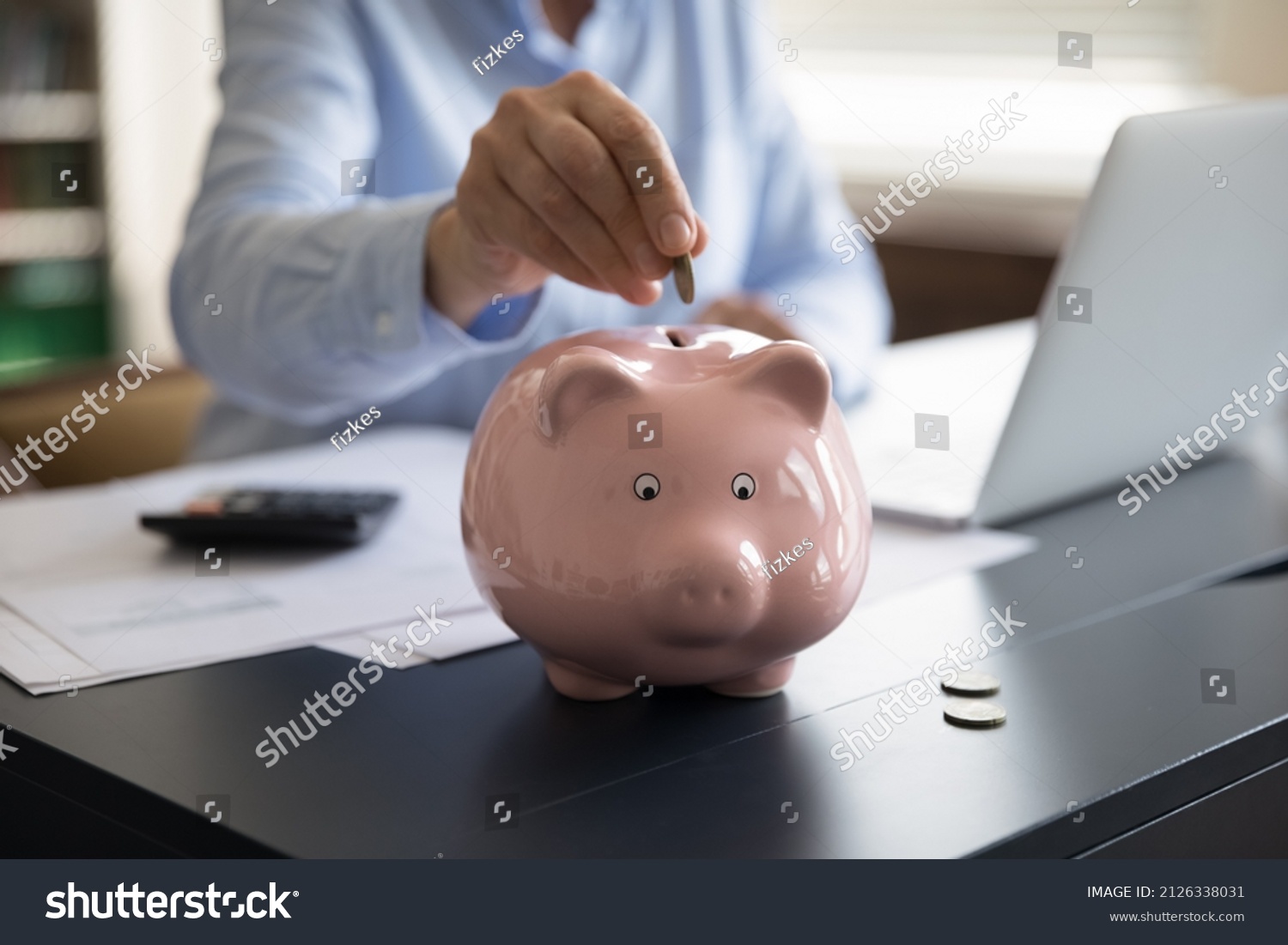Close up cropped middle aged mature woman putting coin in small piggybank, saving money for healthcare medical insurance, planning investment, managing household budget, sitting at table alone at home #2126338031