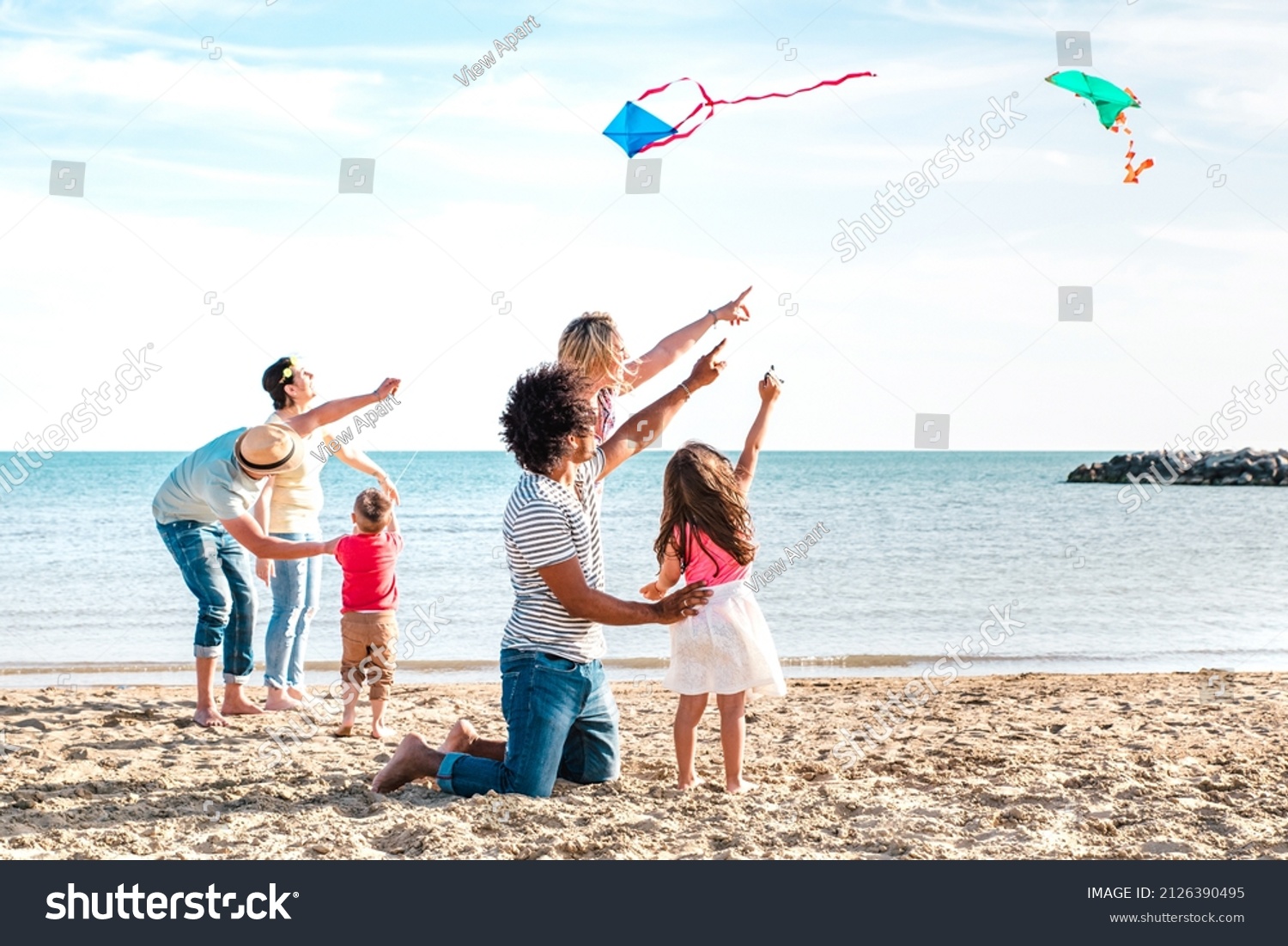 Multiple mixed families composed by parents and children playing with kite at beach vacation - Summer joy life style concept with candid people having fun together at seaside - Bright vivid filter #2126390495