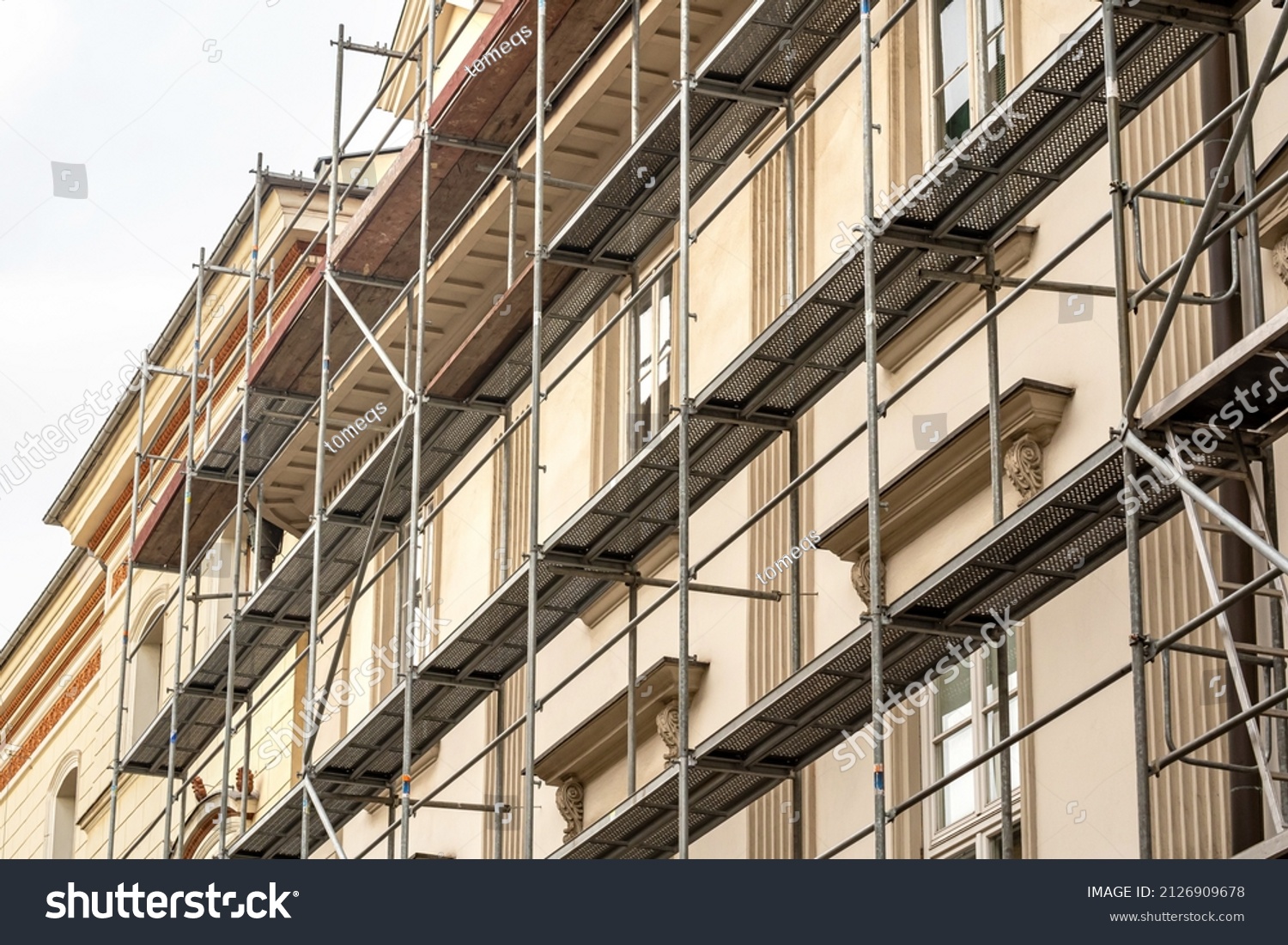 Scaffolding on a generic old tenement house, renovated historical building facade detail, closeup, nobody. Restoration industry, old architecture, real estate renovation simple concept, no people #2126909678