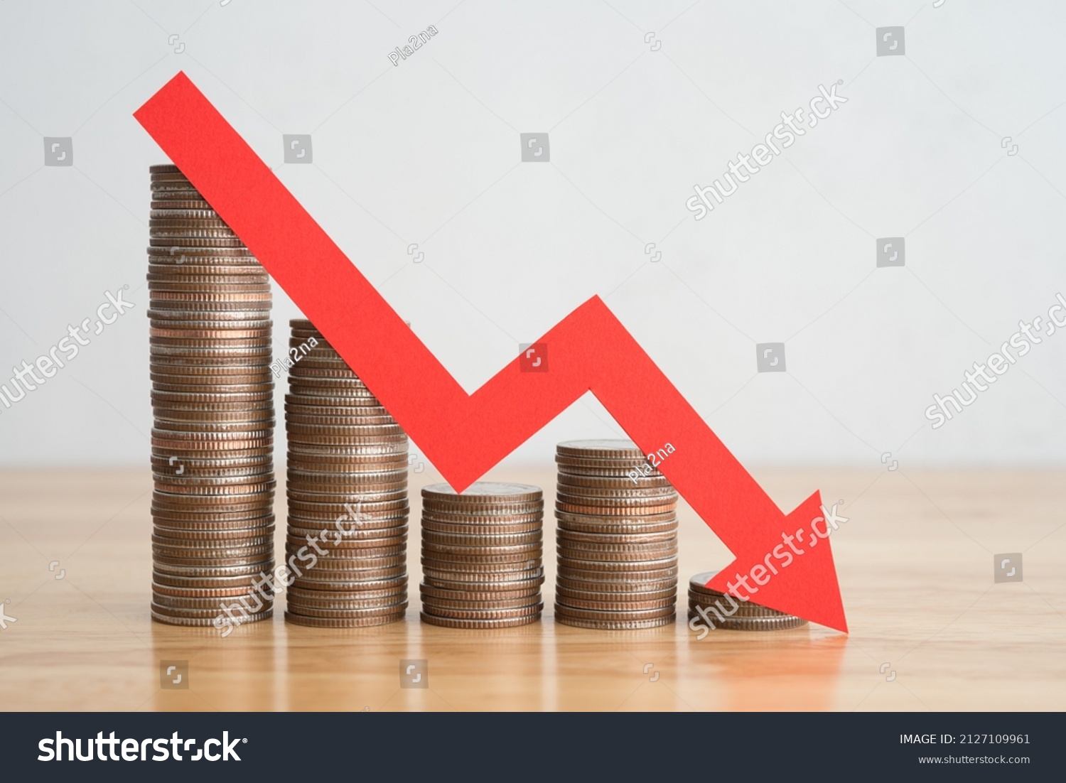 Stack of coins bar chart and red graph trending downwards with white wall background on wooden table copy space. Economy recession crisis, inflation, stagflation, business and financial loss concept. #2127109961