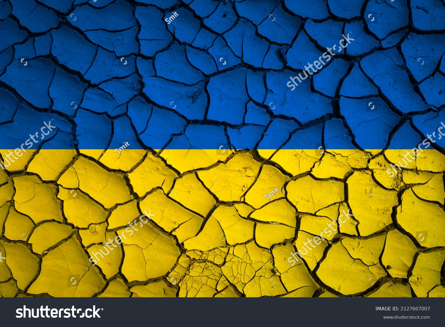 Ukraine national blue and yellow flag on a mud texture of dry cracks on the ground #2127607007