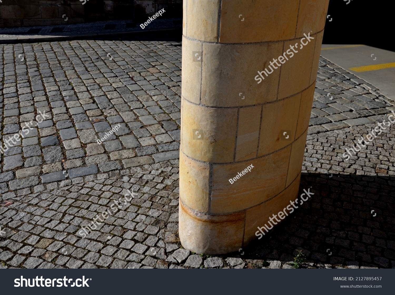 sandstone lookout column made of sandstone blocks in the shape of a cylinder or ellipse. standing on a sidewalk of granite cubes. clean stonemason's work #2127895457