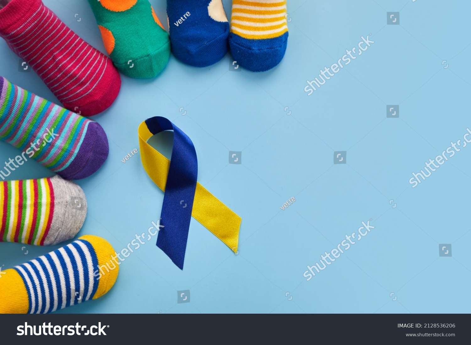 World Down syndrome day background. Down syndrome awareness concept. Socks and ribbon on blue background #2128536206