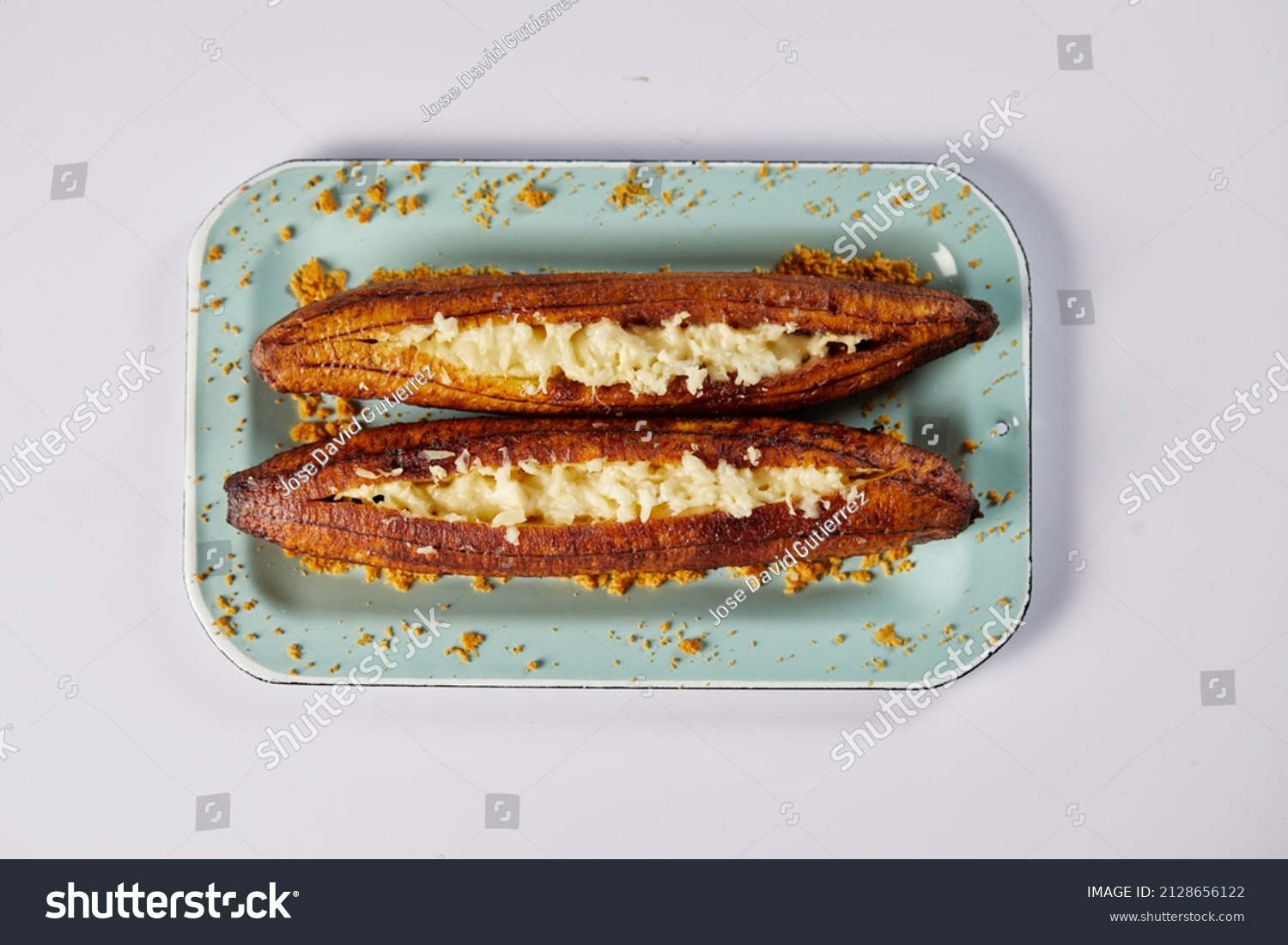 Ecuadorian maduro con queso consists of baked ripe plantains stuffed with cheese. It’s on a white background.  #2128656122