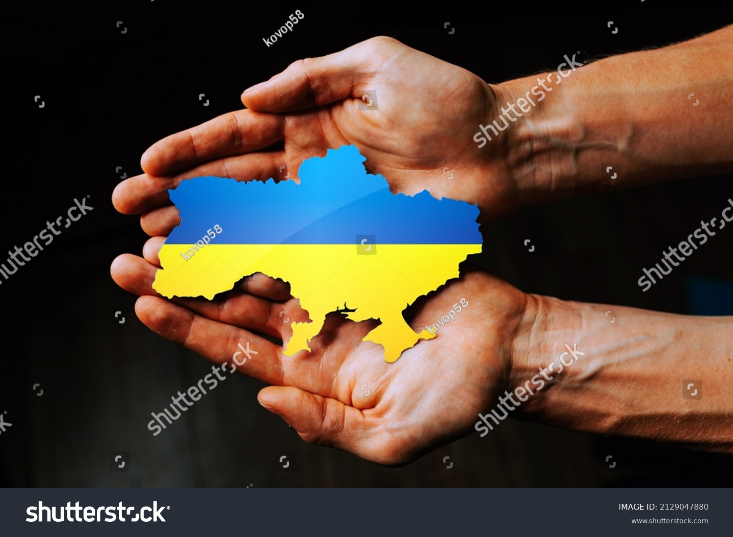 Support for Ukraine in the war with Russia. Hands holding the flag of Ukraine in the shape of the borders of Ukraine. #2129047880