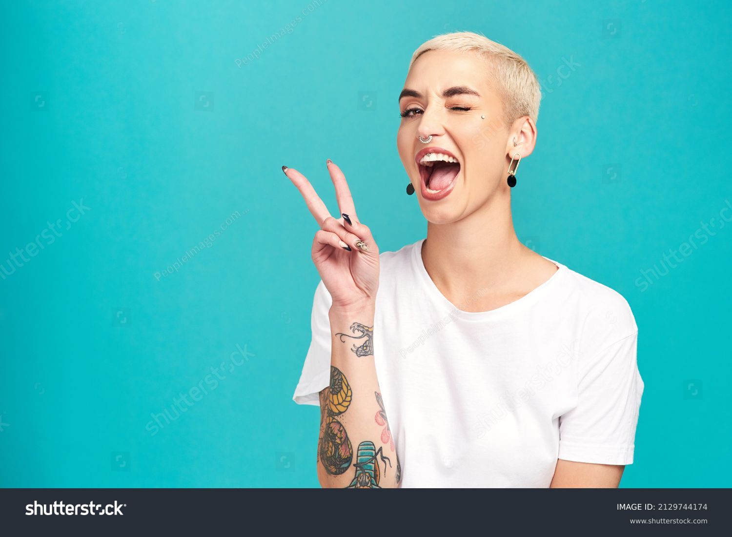 Fill the world with happiness. Studio shot of a confident young woman making a peace gesture against a turquoise background. #2129744174