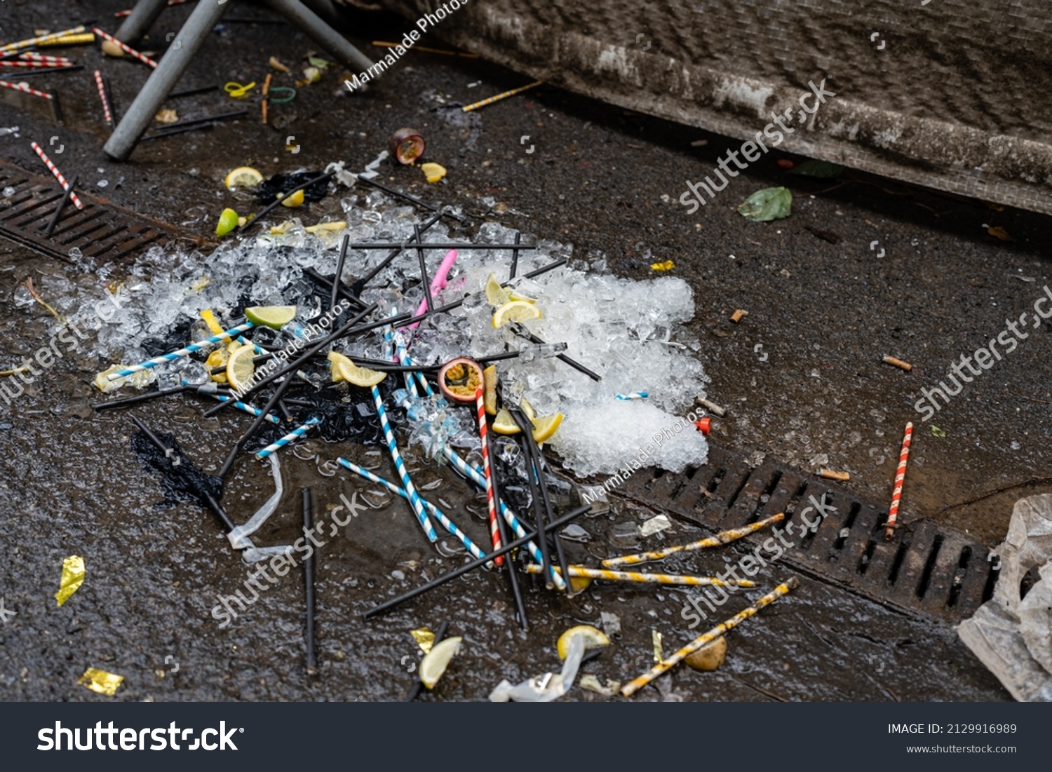 night club rubbish plastic straws lemon and lime wedges and ice cubes left on the floor outside after the night before #2129916989