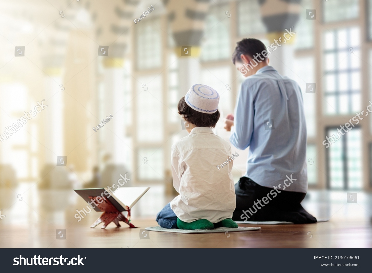 Ramadan Kareem greeting. Father and son in mosque. Muslim family praying. Man and child read Quran and pray. End of fasting. Hari Raya day. Eid al-Fitr celebration. Breaking of holy fast day.  #2130106061