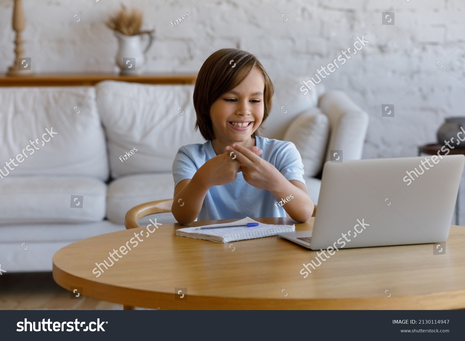 10s boy looking at laptop screen making gestures showing sign language, take part in online class, communicating with tutor using videoconference application with professional speech therapist concept #2130114947